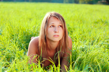 Portrait of young beautiful woman lying on green grass
