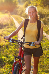 Happy woman cyclist illuminated by sunlight