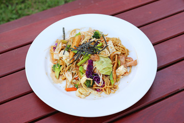 Japanese yakisoba noodles in white plate on wood table.
