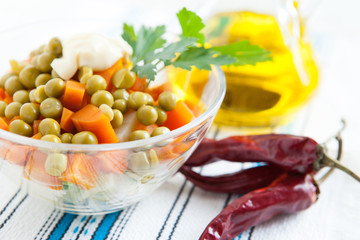 Salad with boiled carrots, canned peas and bottle oil close up