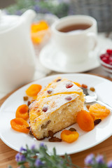 Cheese cake with tea, dried apricot and raisins closeup on a plate