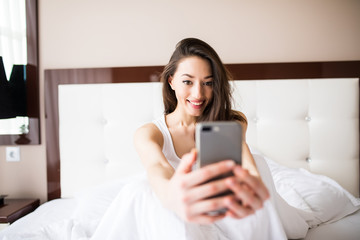 Up selfie portrait sweet joyful girl chilling in bed in the morning.