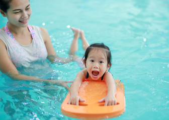 Close up mother teaching kid in swimming pool.