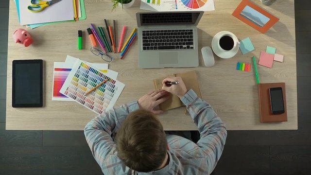 Young male writing down his ideas in notebook, start-up and career, inspiration