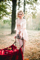 Beautiful and elegant blonde woman with red lips and hair waves wearing beige nightie posing on the...