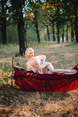 Beautiful and elegant blonde woman with red lips and hair waves wearing beige nightie posing on the...
