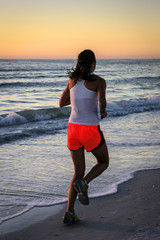 Young woman running along the Siesta Key beach in Florida at sunset