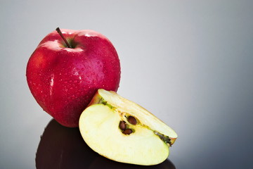 Apple and apple quarter on a reflective surface
