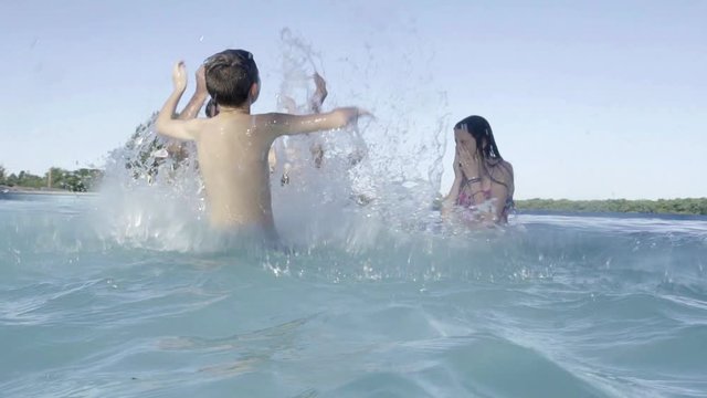 Family in swimming pool splashing each other