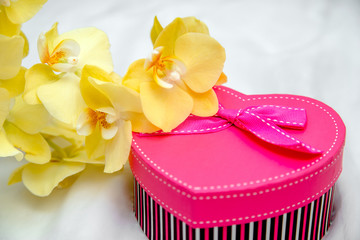 gift box in form of heart on the background of the yellow orchid