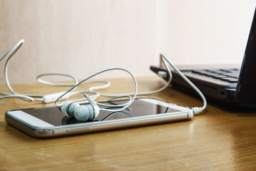 Earphones  white  listen to music  from smartphone put on  a wooden background