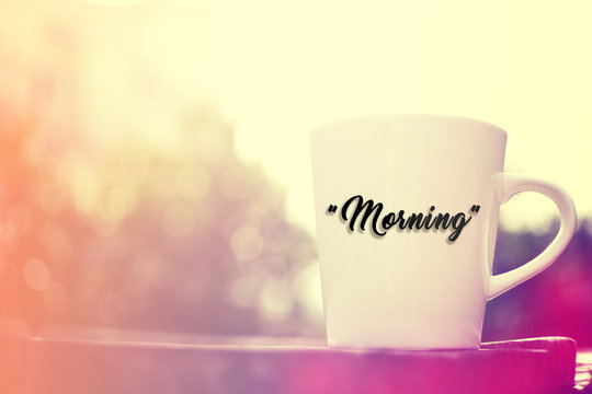 White cup on wooden background. Written "Morning".