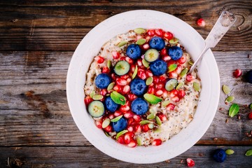 Healthy breakfast bowl porridge with fresh blueberries, pomegranate, mint, chia, flax and pumpkin seeds