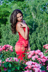 sexy rich girl in a red dress posing in the park