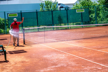 Obraz premium Watering of the ground tennis court with water