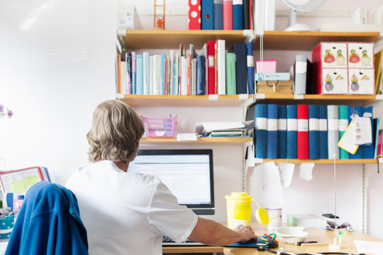 Doctor looking at computer screen in examination room