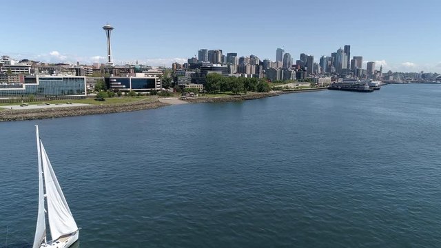 Seattle, WA 05-26-17: Aerial of Sailboat by Piers with Space Needle and Skyscraper Buildings in City Skyline