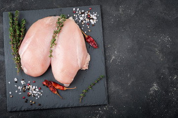 Raw chicken breast for grilled, spices, herbs on dark background, top view. Raw meat chicken for cooking. Delicious balanced food concept. Copy space