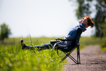 eine Frau sitzt in einem Klappstuhl an einer grünen Wiese und erholt sich