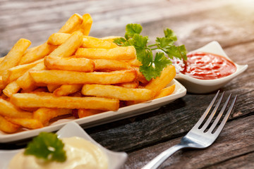 Plate with french fries, parsley, bowls with tomato sauce and mayonnaise and fork