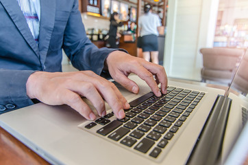 Close-up of business man hands on laptop keyboard. On wooden table is a smartphone .Man is shopping online. Young man surf the Internet on your computer.