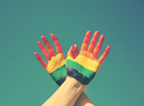 Female hands painted in rainbow gay flag on color background