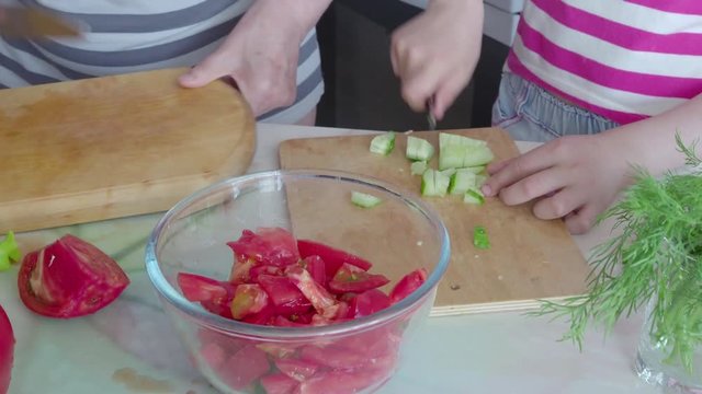 4k, Little girl and her grandmother prepare a vegetable salad in the kitchen.