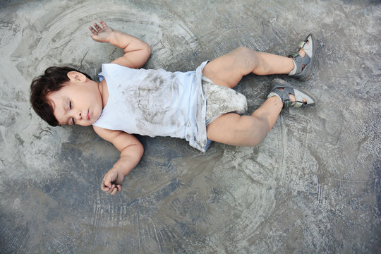 Little dirty baby boy lying on the muddy floor