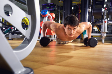 Fototapeta na wymiar A man does push-ups from floor in the gym.