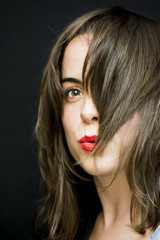 Fototapeta premium Portrait of a beautiful woman shaking her hair on black background
