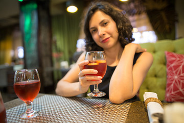A girl drinks a red strawberry drink in a restaurant