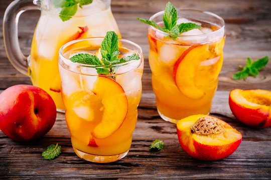 Summer cold drinks: homemade peach sangria with ice cubes, and mint in glasses