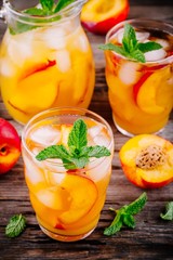 Summer cold drinks: homemade peach ice tea with ice cubes, and mint in glasses