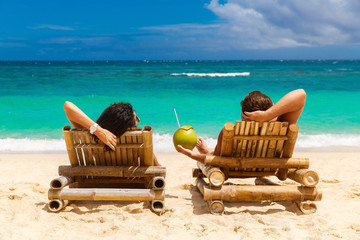 Beach summer couple on island vacation holiday relax in the sun on their deck chairs on the...