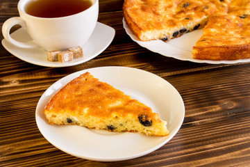 Cottage cheese casserole with raisins and tea on tne wooden background