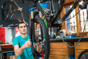 Male master is repairing the bicycle in a special workshop