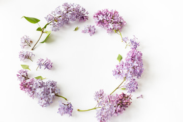 Flat lay top view photo of spring composition. Wreath made of lilac flowers on white background.