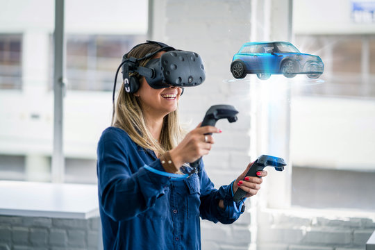 A woman wearing a virtual reality headset looks at a 3D model of a car.