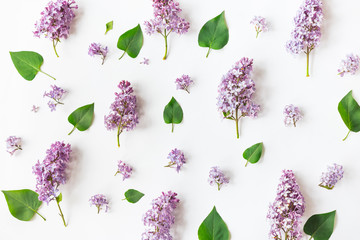 Flat lay top view photo of a pattern made of a lilac flowers, leaves and petals.