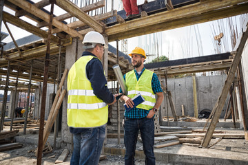 Man in hardhat and green jacket posing on building site