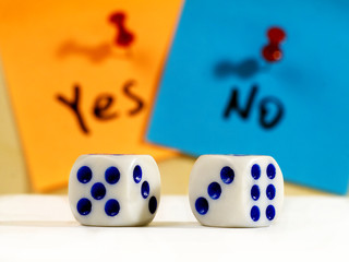 two dices and yes and no words on sticky notes in background