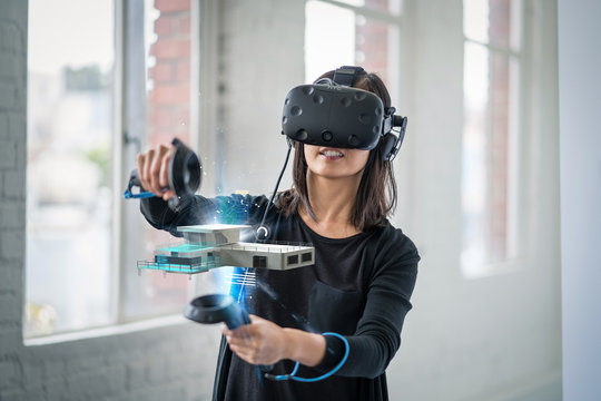 A woman wearing a virtual reality headset interacts with 3D objects.