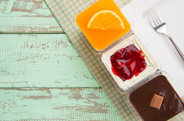 chocolate cake orange cake and strawberry cake in plastic cup on wood table