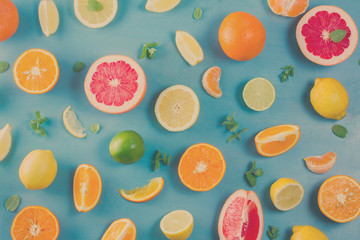 citrus food pattern on blue background - assorted citrus fruits with mint leaves, retro toned