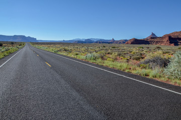 Fototapeta na wymiar empty country road in grasslands with flat top mountains in the background UT-211 Scenic Highway, Canyonlands National Park, Utah, United States