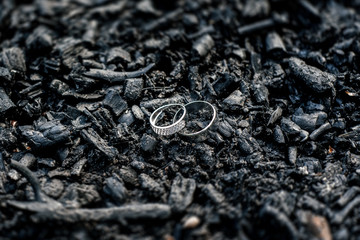 Golden wedding rings on black charcoa, selective focus, tilt-shift, free space