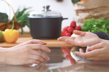 Close-up of human hands are gesticulate over a table in the kitchen. Women choosing menu or making online shopping. So much ideas for tasty cooking. Vegetarian, healthy meal and friendship concept