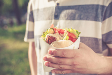 Man is holding falafel sandwich in paper bag