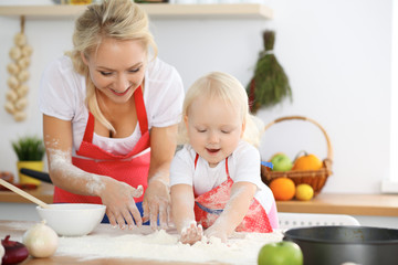 Mother and her little daughter cooking holiday pie or cookies for Mother's day. Concept of happy family in the kitchen