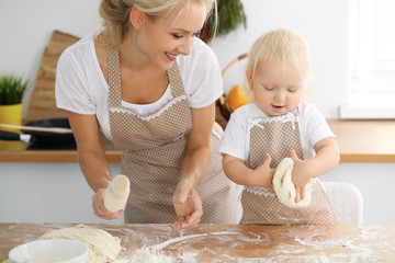 Mother and her little daughter cooking holiday pie or cookies for Mother's day. Concept of happy...